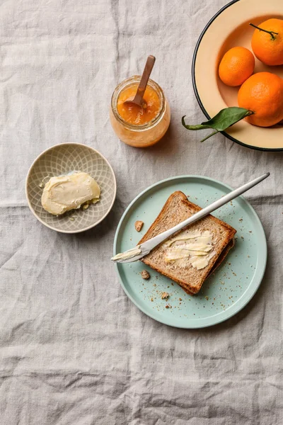 Bread with butter and tasty tangerine jam on table