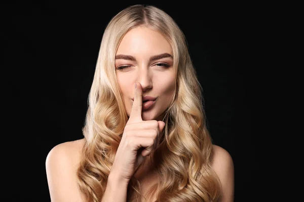 Young woman with beautiful curly hair showing silence gesture on color background