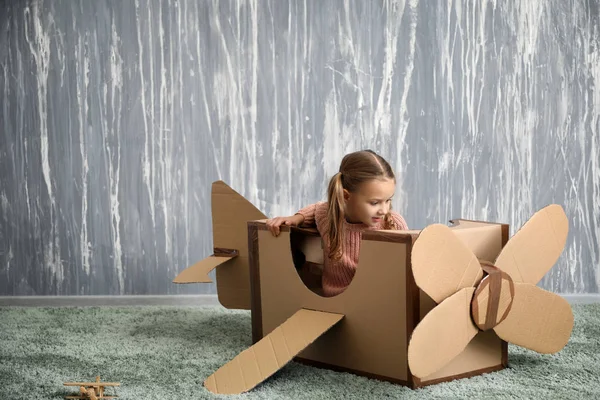 Küçük kız odasında karton uçak ile oynarken
