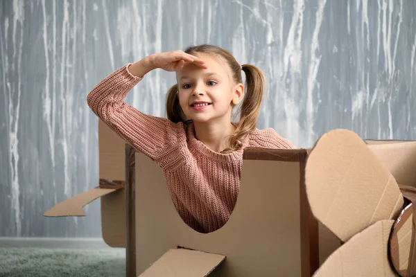 Küçük kız odasında karton uçak ile oynarken