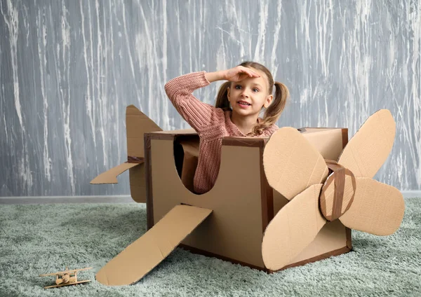 Küçük kız odasında karton uçak ile oynarken