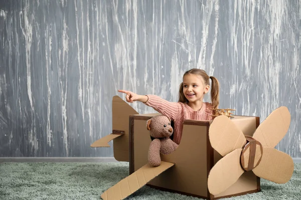 Küçük kız odasında karton uçak ile oynarken