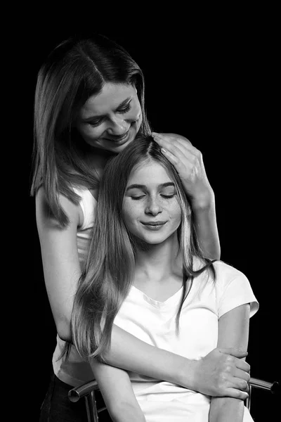 Black and white portrait of happy mother and daughter on dark background