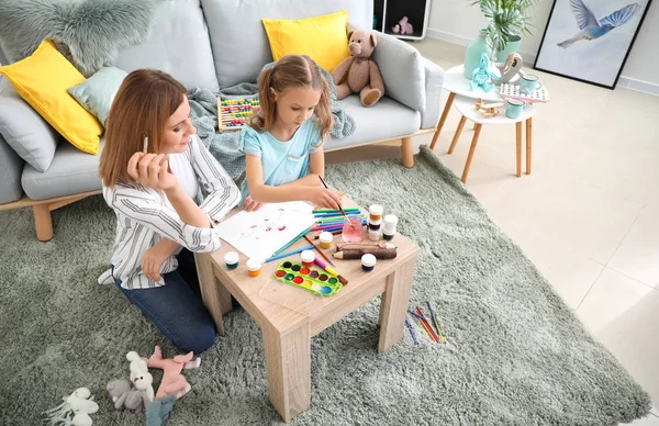 Happy mother with daughter painting at home