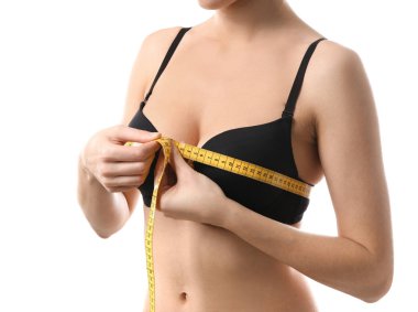 Beyaz arka planda göğüslerini ölçen genç bir kadın.