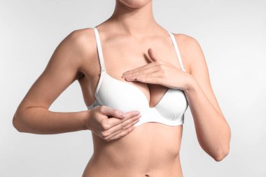 Genç kadın göğüslerini ışık arka plan üzerinde kontrol. Kanser farkındalık kavramı