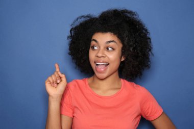 Renk arka plan üzerinde yükseltilmiş işaret parmağı olan Afrikalı-Amerikalı kadın portresi