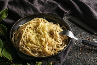 Karanlık tablo üzerinde tavada peynirli lezzetli makarna