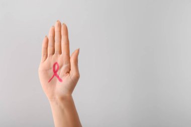 Pembe kurdele avucunun karşı açık renkli çizilmiş olan kadın. Meme kanseri bilinçlendirme kavramı