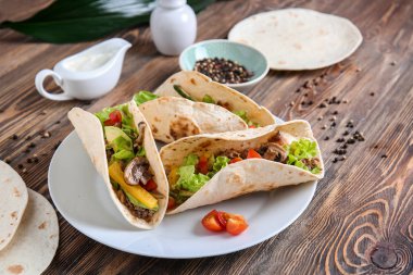 Ahşap masa üzerinde lezzetli tacos ile plaka