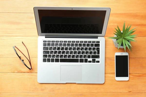 Laptop, phone, glasses and succulent on wooden table