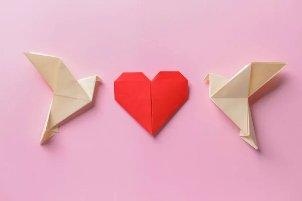 Origami birds and heart on color background
