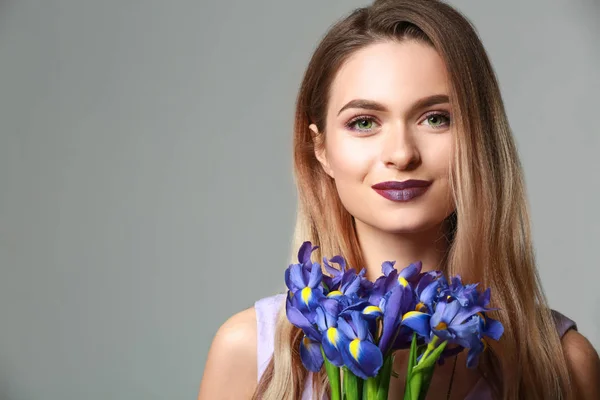 灰色の背景の上に花の花束と美しい若い女性 — ストック写真