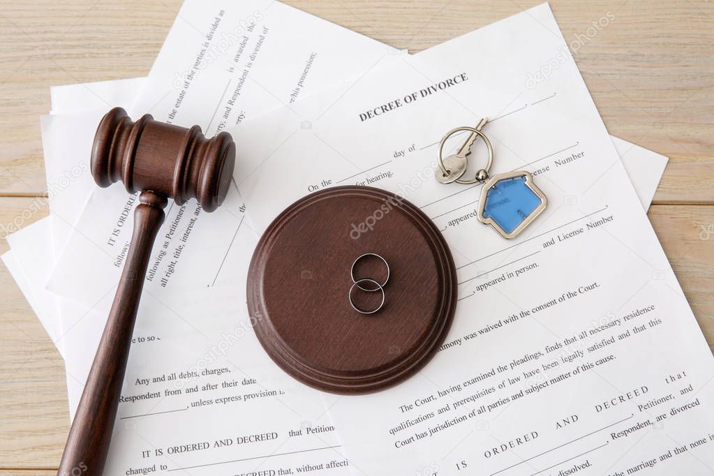 Rings with decree of divorce, judge gavel and key from house on table. Concept of dividing marital property