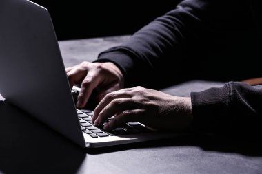Koyu arka plan üzerinde closeup masada oturan dizüstü bilgisayar ile profesyonel hacker