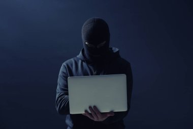 Koyu arkaplanda dizüstü bilgisayarı olan profesyonel bir hacker.