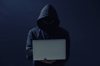 Koyu arkaplanda dizüstü bilgisayarı olan profesyonel bir hacker.
