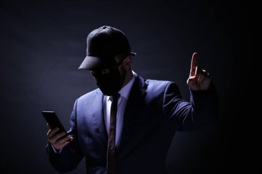 Profesyonel hacker koyu arka plan üstünde hareket eden telefon ile. İnternet hırsızlığı kavramı