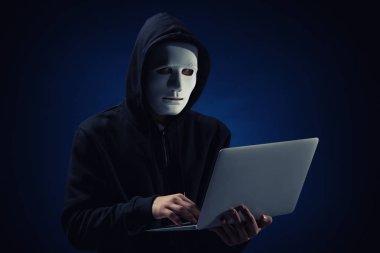Profesyonel hacker maskesi ve koyu arka plan üstünde laptop