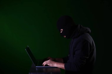 Koyu arkaplanda dizüstü bilgisayarı olan profesyonel bir hacker.