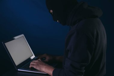 Koyu arkaplanda dizüstü bilgisayarı olan profesyonel bir hacker.