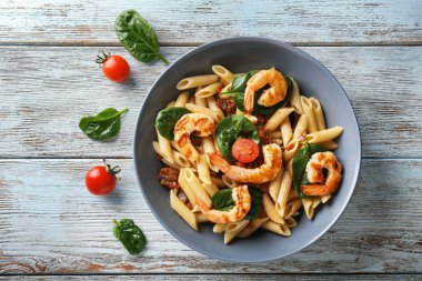 Lezzetli makarna karides ve ahşap masa üzerinde bir kapta domates ile
