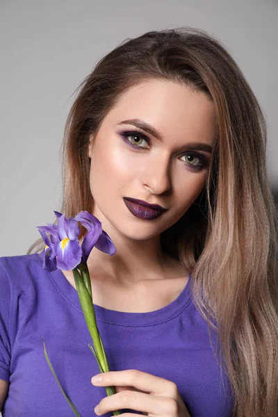 灰色の背景に花を持つ美しい若い女性 — ストック写真