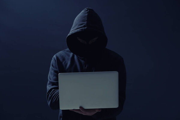Профессиональный хакер с ноутбуком на темном фоне