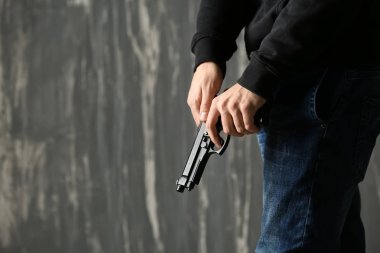Gri arka plan üzerinde silahla erkek suçlu