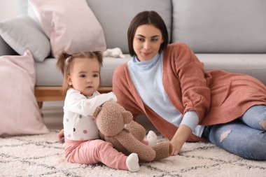 Genç kadın sevimli küçük kızıyla birlikte evde oynarken