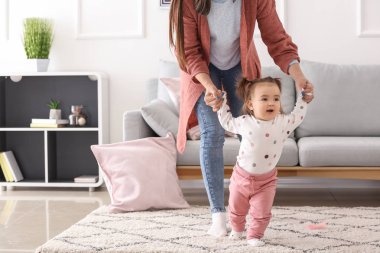Genç kadın evde yürümeyi sevimli küçük kızını öğretim