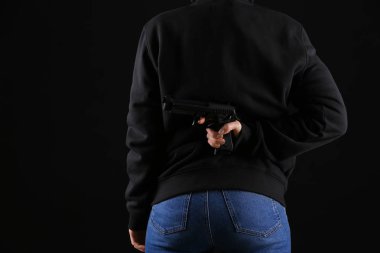 Silah koyu arka plan üzerinde arkasına saklanarak kişi