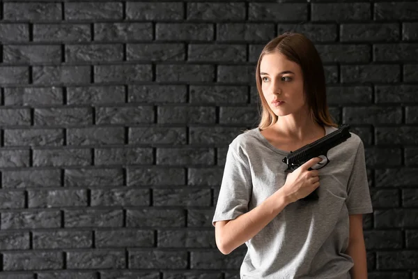 Jovem Mulher Com Uma Arma Fundo Tijolo Escuro — Fotografia de Stock