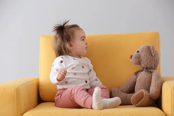 可爱的女婴与玩具熊坐在扶手椅在光的背景 — 图库照片