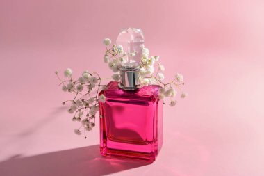 Renkli arka planda bir şişe parfüm ve çiçekler