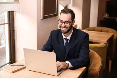 Kafede dizüstü bilgisayarda çalışan genç işadamı.