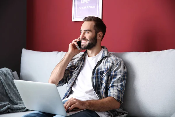 Ung Frilansare Talar Mobiltelefon Medan Arbetar Laptop Hemma — Stockfoto