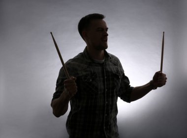 Gri arka plan üzerinde sopaları ile genç adam silüeti