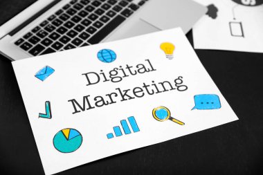 Karanlık tablo üzerinde dijital pazarlama metin ile laptop ve kağıt levha