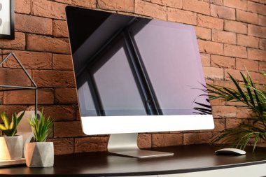 Modern bilgisayar tuğla duvarın yanındaki masada.