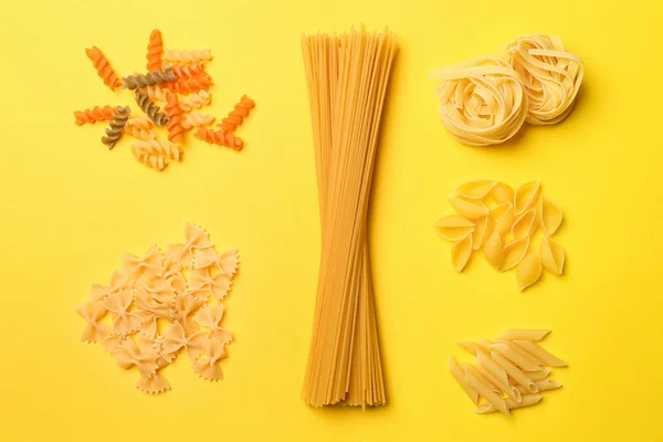 Assortment of uncooked pasta on color background