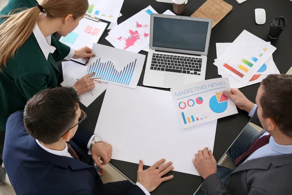 Young colleagues with blank sheet of paper working together at table