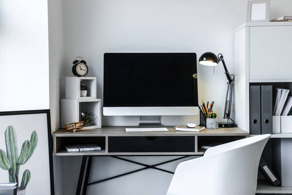 Stylish workplace with modern computer near white wall