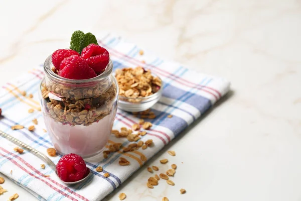 Ahududu ve masada yulaf ezmesi ile lezzetli yoğurt cam kavanoz