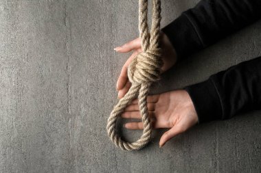 Female hands and rope with loop on grey background. Suicide concept clipart