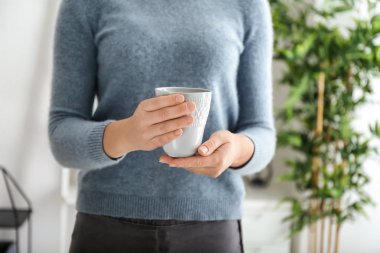 Young woman with cup of hot coffee at home