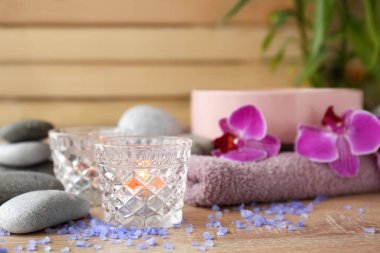 Ahşap masada deniz tuzu ve aksesuarları ile tutucularda mum yakma