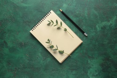 Defter ile yeşil okaliptüs dalları ve kalem renk arka plan üzerinde