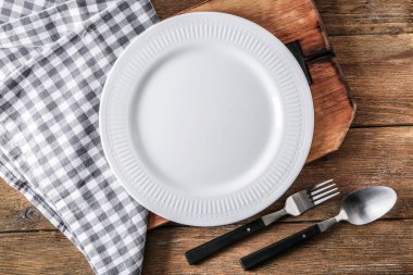 Ahşap arka plan üzerinde çatal bıçak takımı, peçete ve tahta ile boş seramik plaka