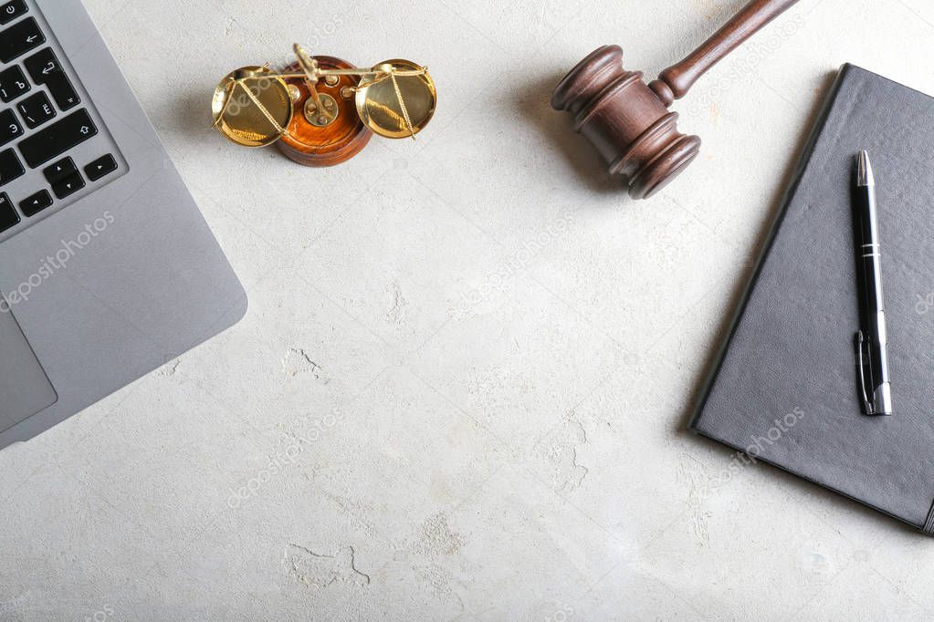 Judge's gavel, notebook, laptop and scales of justice on light background